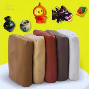 Puede incluir: Bloques de arcilla de varios colores, en tonos marrón, beige, rojo, marrón oscuro y blanco. Encima de la arcilla, pequeñas figuras decorativas, como un pollito de dibujos animados, un dragón negro y una fresa.