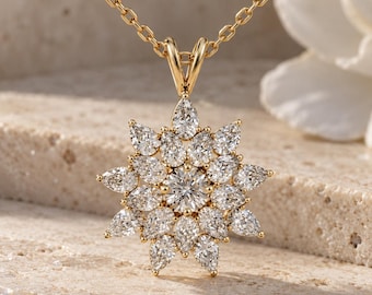 May include: A gold pendant necklace featuring a central round brilliant-cut diamond surrounded by multiple layers of pear-shaped diamonds arranged in a starburst or floral pattern, suspended from a delicate gold chain with oval links.