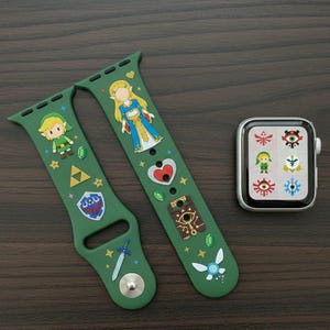 Pode incluir: Pulseiras de relógio verdes com desenhos de personagens de desenhos animados e um smartwatch prateado. As pulseiras apresentam personagens e símbolos de uma popular série de videojogos. O smartwatch exibe ícones correspondentes.