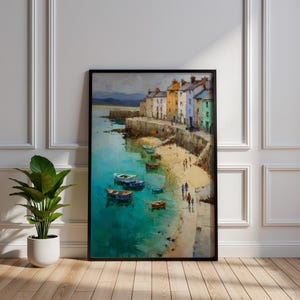 May include: A framed oil painting depicts a coastal scene with colorful buildings, boats, and people on a beach. The water is a vibrant turquoise, and the sky is overcast. The artwork is in a black frame and leans against a white wall.