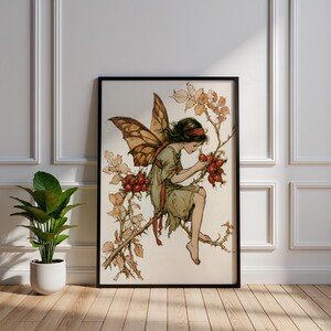 Può includere: Una stampa artistica incorniciata raffigurante l'illustrazione di una fata con grandi ali marroni, che indossa un abito verde chiaro e una fascia rossa, seduta su un ramo spinoso decorato con grappoli di piccole bacche rosse e foglie marrone chiaro.