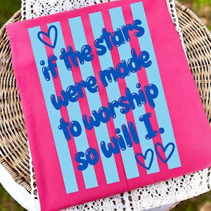 Peut inclure: Un textile rectangulaire rose avec des rayures verticales bleues et le texte "if the stars were made to worship so will I." Le texte est dans une police ludique, avec des coeurs en haut et en bas.