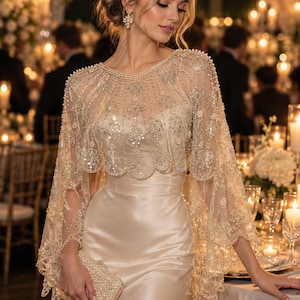Puede incluir: Un vestido largo de satén color champán combinado con una capa transparente de bordes festoneados con intrincados bordados dorados, lentejuelas y adornos de perlas. Se sostiene un bolso de mano rectangular a juego cubierto de pequeñas perlas blancas.