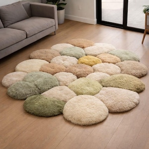 Könnte beinhalten: Ein runder Teppich aus vielen flauschigen, runden Kissen in verschiedenen neutralen Farben wie Beige, Grün und Gelb. Der Teppich liegt auf einem Holzboden und bildet eine weiche, einladende Oberfläche.