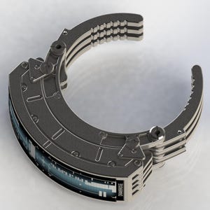 May include: A futuristic, metallic gray bracelet with a digital display. The bracelet features a segmented design with multiple layers and a locking mechanism. The text "DRAWBRIDGE" is visible on the display.