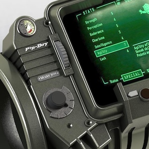 May include: A close-up of a Pip-Boy Model 3000, a wrist-mounted device with a green screen displaying stats. The device has a gauge, a slider, and a dial. The screen shows stats for Strength, Perception, Endurance, Charisma, Intelligence, Agility, and Luck.