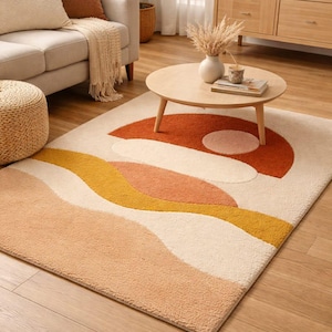 Peut inclure: Tapis rectangulaire avec un fond crème et un motif abstrait. Il présente un grand demi-cercle orange, un petit cercle rose et des lignes ondulées pêche et jaune. Le tapis est posé sur un sol en bois. Les dimensions du tapis sont en centimètres.