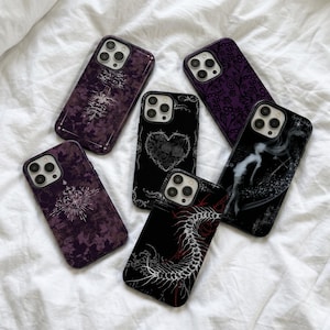 May include: Five smartphone cases featuring dark designs. One has a purple floral pattern, one a white tree graphic, one a heart-shaped skull illustration, one a purple lace pattern, and one a white centipede graphic on a black background.