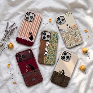 May include: Five smartphone cases featuring cat illustrations. One has stripes and a black cat, one has a floral pattern with cats, one is split between wood grain and floral, one is deep red with a black cat, and one is cream and brown.