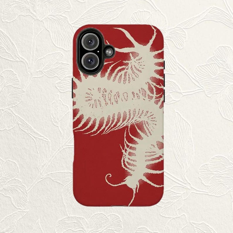 K&ouml;nnte beinhalten: Eine rechteckige Smartphone-H&uuml;lle mit tiefrotem Hintergrund und einer gro&szlig;en, cremewei&szlig;en Grafik eines skelettierten Tausendf&uuml;&szlig;lers, die sich &uuml;ber die Oberfl&auml;che schl&auml;ngelt. Die H&uuml;lle hat eine kreisf&ouml;rmige Kameraaussparung mit zwei Linsen.