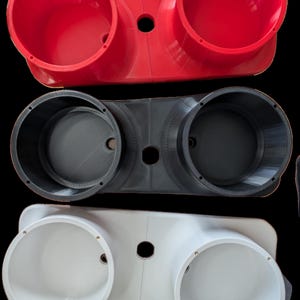 May include: Three 3D-printed plastic components in red, gray, and white. Each piece features two large, circular openings and a central hole. The red and white pieces have a glossy finish, while the gray one appears matte.