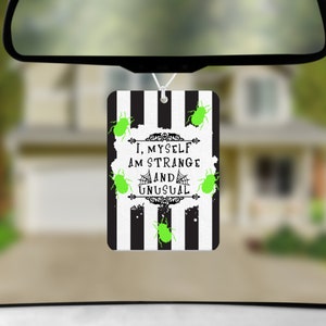 May include: Black and white striped car air freshener with green bugs and the text "I, myself am strange and unusual".