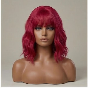Puede incluir: Peluca corta y ondulada de color magenta vibrante. Presenta un flequillo recto y se muestra sobre una cabeza de maniquí. El cabello tiene una textura natural y está diseñado para enmarcar el rostro.