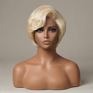 Könnte beinhalten: Blonde, kurz geschnittene Perücke mit Seitenscheitel, präsentiert auf einem Schaufensterkopf. Die Perücke hat einen natürlichen Haaransatz und eine weiche, wellige Textur. Der Schaufensterkopf hat einen neutralen Hautton und steht vor einem schlichten Hintergrund.