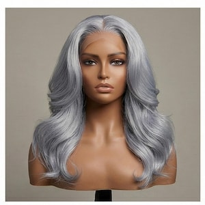 May include: A silver-gray wig with long, wavy hair. The wig features a lace front and is styled with voluminous curls. The mannequin head is displayed against a neutral background, showcasing the wig's color and texture.