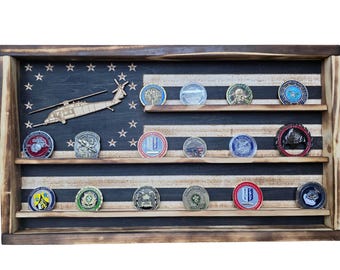 May include: A wooden display case with a flag design, featuring a dark blue background with white stars and alternating white and black stripes. The case holds various military challenge coins, and a wooden helicopter cutout.