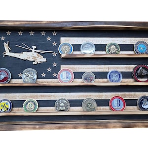 May include: A wooden display case with a rustic finish, designed to resemble the American flag. It features three shelves holding various military challenge coins. A wooden helicopter and star cutouts decorate the blue section.
