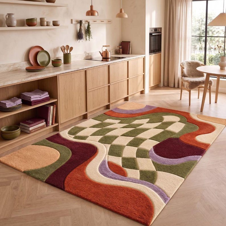 May include: A rectangular area rug featuring a tufted texture with a central checkered pattern in olive green and cream. The design includes wavy, organic shapes in shades of burnt orange, deep burgundy, lavender, and tan, creating a layered effect.