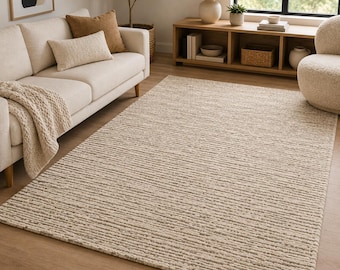Könnte beinhalten: Ein rechteckiger Teppich mit einem strukturierten, linearen Muster in Beige- und Cremetönen. Der Teppich weist ein flaches Gewebe mit horizontalen Streifen auf, die eine subtil gerippte Oberflächenoptik über den gesamten Bodenbelag erzeugen.