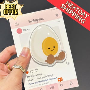 May include: A clear acrylic card designed as an Instagram post, featuring a cartoon egg with a smiling face and brown feet. The card has a pink border and includes the Instagram logo and the text "Album. Thank you for liking it." A "Best Offer" sticker is in the top left.