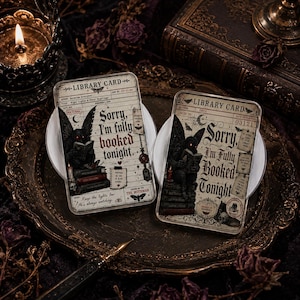 May include: Two rectangular acrylic plaques designed as vintage library cards featuring a Mothman illustration reading a book on a stack of volumes. The text reads, Sorry, I'm fully booked tonight, with additional library card details and motifs.