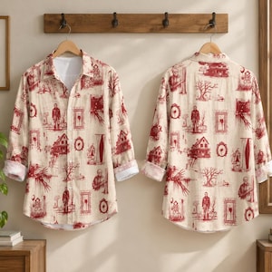 May include: A long-sleeve button-down shirt featuring an all-over red print on a cream background. The pattern consists of various horror-themed illustrations, including houses, trees, and figures, displayed in a repeating, toile-style layout.