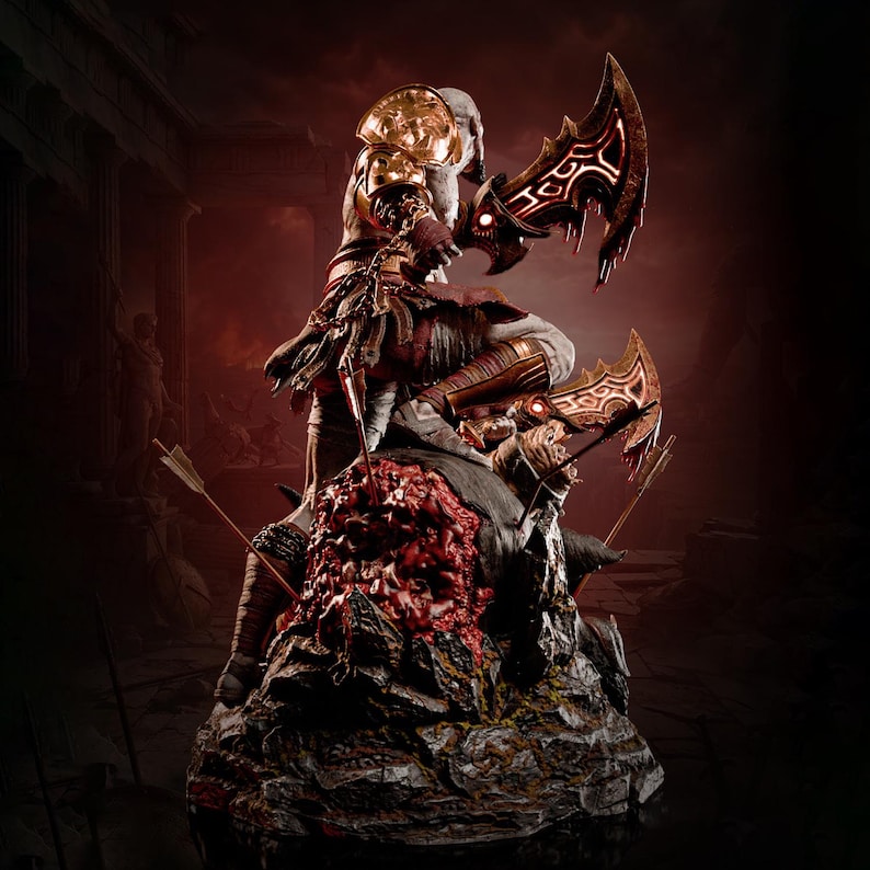 May include: A detailed collectible statue of a warrior figure with pale skin, wearing gold shoulder armour and brown wraps, wielding two glowing red-bladed curved swords. The figure stands atop a dark, rocky base embedded with arrows.