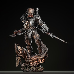 May include: A detailed Predator statue, depicting the alien hunter in a dynamic pose. The figure is clad in armour and holds bladed weapons. It stands on a base adorned with skulls and a tree trunk, with a dark background.