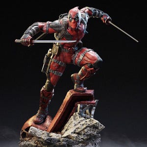 May include: A detailed statue of Deadpool in a dynamic pose, clad in a red and black suit with a mask. He is holding two katanas, standing on a stone base. The figure has intricate details and a comic book aesthetic.