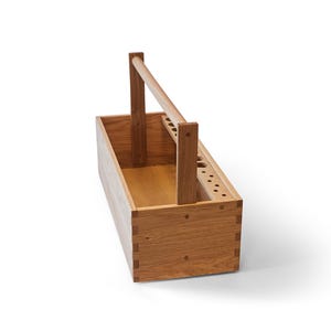 May include: A wooden tool box with a handle. The box is made of light brown wood and has a rectangular shape. The handle is attached to two vertical supports, and the box has several holes for tools.
