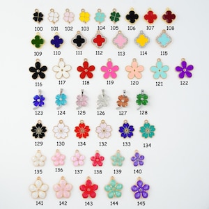 May include: A collection of gold-toned metal charms in various floral and clover designs. The charms are in a variety of colors, including black, white, red, pink, and blue. Each charm has a small loop for attaching to jewelry or other crafts.