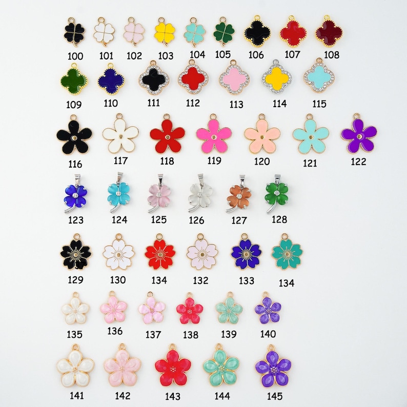 May include: A collection of gold-toned metal charms in various floral and clover designs. The charms are in a variety of colors, including black, white, red, pink, and blue. Each charm has a small loop for attaching to jewelry or other crafts.