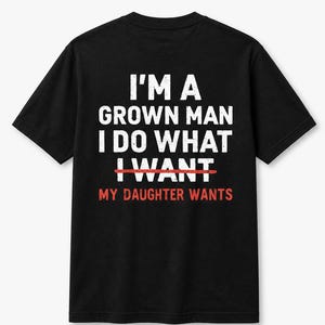 Puede incluir: Camiseta negra con texto blanco que dice "I'M A GROWN MAN I DO WHAT I WANT", con "I WANT" tachado en rojo, y "MY DAUGHTER WANTS" en rojo debajo. La camiseta es de cuello redondo y manga corta.