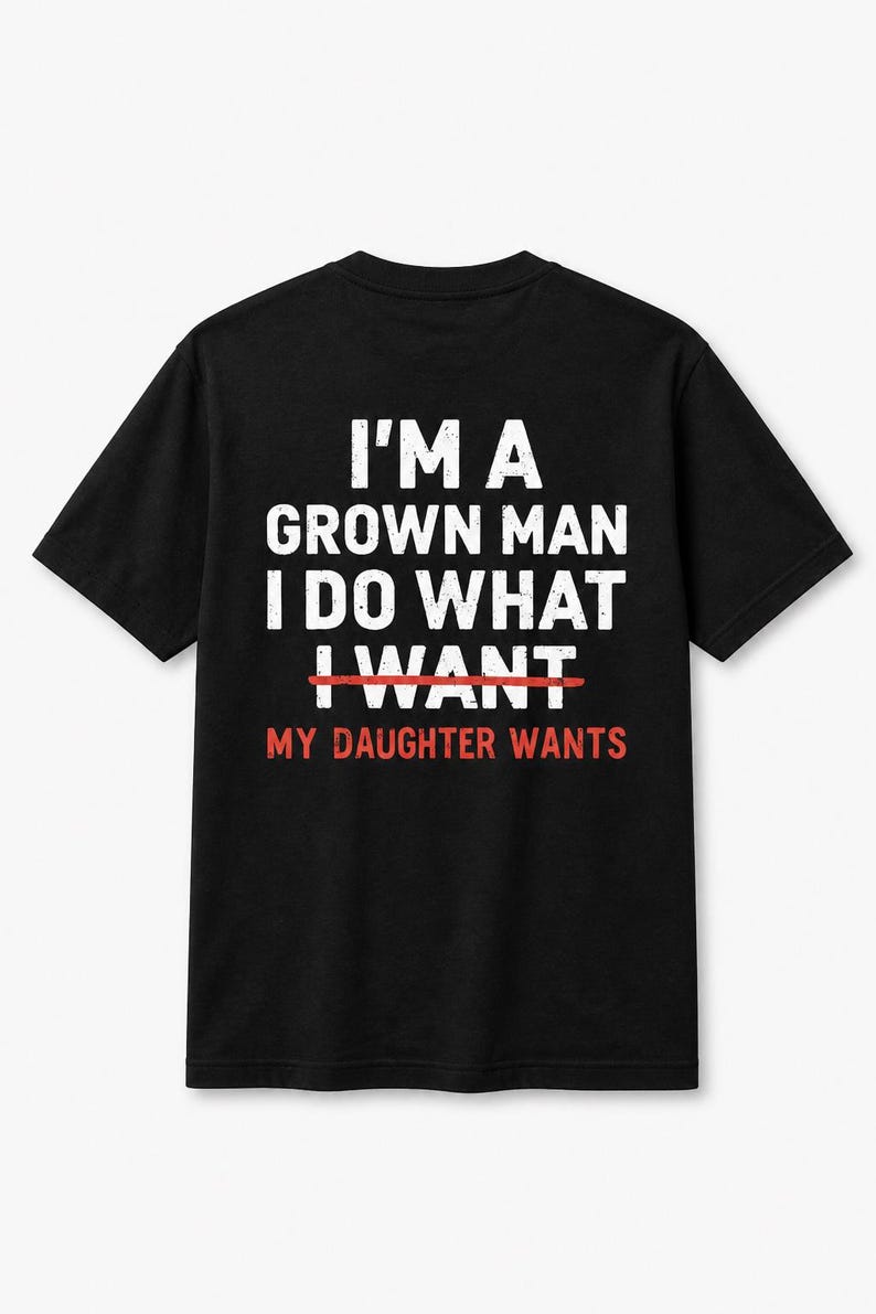 Puede incluir: Camiseta negra con texto blanco que dice "I'M A GROWN MAN I DO WHAT I WANT", con "I WANT" tachado en rojo, y "MY DAUGHTER WANTS" en rojo debajo. La camiseta es de cuello redondo y manga corta.