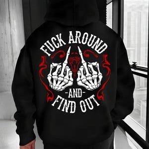 May include: Black hoodie with a graphic on the back featuring white skeleton hands giving the middle finger, red accents, and the text "FUCK AROUND - AND - FIND OUT" in white.