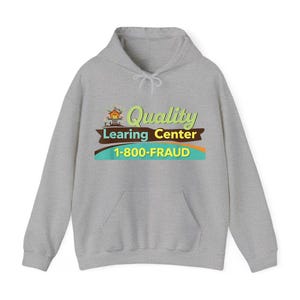 May include: A light gray hoodie with a front pocket and drawstring hood. The front features a colorful graphic with the words "Quality Learing Center" and the phone number "1-800-FRAUD".