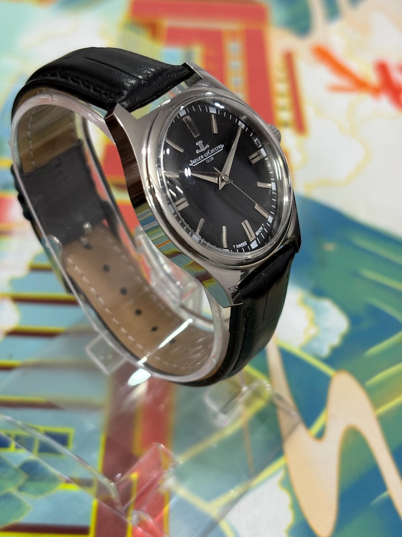 The black dial enhances readability while adding a bold and sophisticated touch, perfect for those who appreciate minimalist luxury watches. This close-up emphasizes the originality and condition of the dial, an important factor for vintage watch buyers seeking authenticity and quality. Ideal for collectors of Swiss watches, retro watches, and luxury dress watches, this Jaeger-LeCoultre Club model is a rare find.