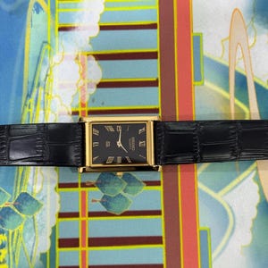 May include: A rectangular gold-toned watch with a black face and black leather band. The watch face features gold Roman numerals and the text "SEIKO QUARTZ". The watch band is textured with a crocodile pattern.