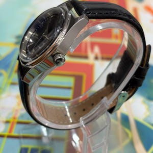 Suitable for gifting occasions such as birthdays, anniversaries, or special celebrations. Keywords: Jaeger-LeCoultre dial close up, black dial vintage watch, Swiss watch detail, luxury watch face, mechanical watch dial, vintage wristwatch close view, collectible watch detail, classic timepiece design, authentic Swiss watch, retro luxury watch, men’s dress watch dial.