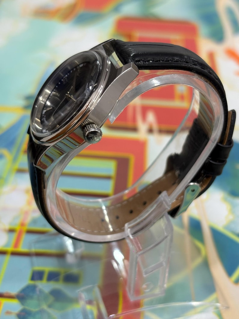 Suitable for gifting occasions such as birthdays, anniversaries, or special celebrations. Keywords: Jaeger-LeCoultre dial close up, black dial vintage watch, Swiss watch detail, luxury watch face, mechanical watch dial, vintage wristwatch close view, collectible watch detail, classic timepiece design, authentic Swiss watch, retro luxury watch, men’s dress watch dial.