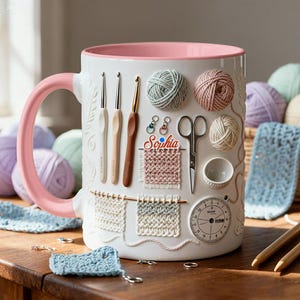 May include: White ceramic mug with a pink handle and rim, decorated with crochet tools, yarn balls, and the name "Sophia." The mug features a textured design with crochet hooks, scissors, and a gauge. A charming gift for a crochet enthusiast.