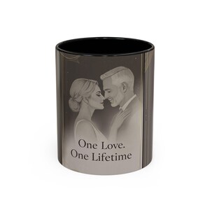 以下が含まれることがあります： ロマンチックなカップルのイラストが描かれた、白黒のセラミックマグカップ。「One Love. One Lifetime」の文字がプリントされています。マグカップの内側は黒で、金色の縦縞があります。