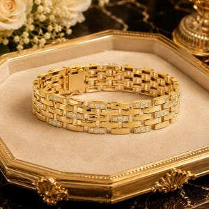 May include: A gold link bracelet featuring a repeating pattern of polished rectangular metal segments. Every other link is accented with a row of three small, clear, round-cut stones embedded into the surface. The bracelet has a secure clasp.