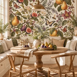 May include: A dining nook featuring a round wooden pedestal table with two woven chairs, set against a wall covered in botanical wallpaper depicting figs, pears, butterflies, and bees. A ceramic bowl of fruit sits on the table.