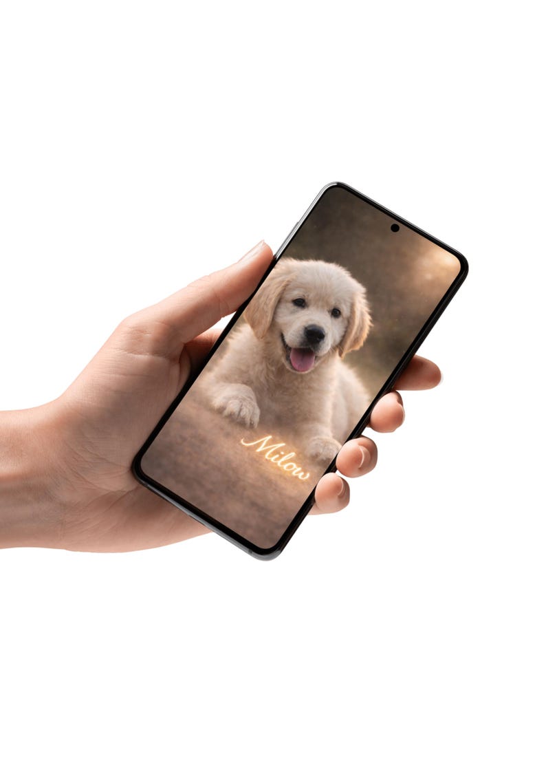 May include: A smartphone displays a smiling golden retriever puppy with the name "Milow" in a cursive font. The puppy has light brown fur and is lying down. The phone has a black frame.