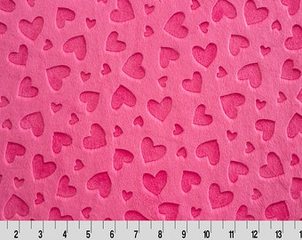 May include: Pink fabric with a repeating pattern of embossed hearts. The hearts are of varying sizes and are cut out of the fabric.