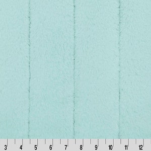 May include: A close-up of a light blue fuzzy fabric with a textured surface. The fabric is divided into 15 sections by thin lines.