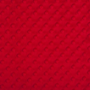 May include: A solid red, rectangular fabric with a rounded corner design. The fabric has a textured surface with evenly spaced, raised, circular bumps. The overall appearance is a vibrant, consistent red color.