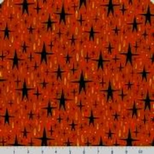 May include: Close-up of a fabric with a repeating pattern of black stars and smaller starbursts on a reddish-orange background. The design includes small, elongated gold shapes and tiny white dots, creating a celestial theme.