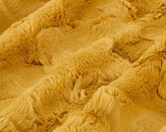 Puede incluir: Primer plano de una tela suave y afelpada de color amarillo mostaza cálido. La tela tiene una textura peluda y un patrón ligeramente ondulado.